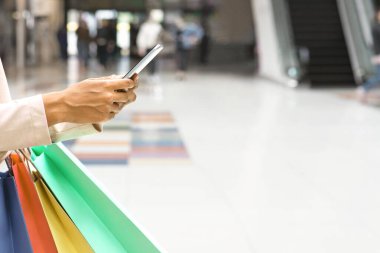 Alışveriş Uygulaması. Kâğıt Torbası Taşıyan, AVM 'de Akıllı Telefon kullanan, Online İndirim Teklif Verenleri Kontrol eden, Satın Alım Yapan, Kopya Boşluklu Kesilmiş Görüntü