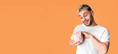 Tasarruf kavramı. Sarı arka planda domuz kumbarasını okşayan gülünç adam, boş alan