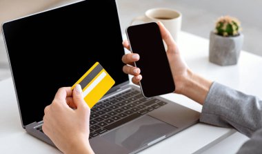 Online shopping from home during quarantine. Girl near laptop holds smartphone and credit card clipart