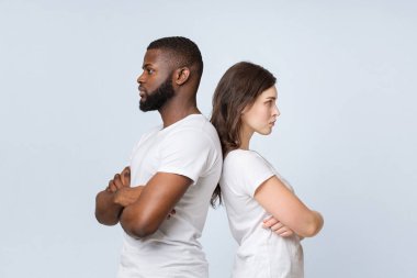 Irklar arası sorunlar. Kızgın genç kadın ve siyah adam sırt sırta dururlar, tartışmadan sonra birbirlerini görmezden gelirler, serbest alan ile aydınlık bir arka plan.