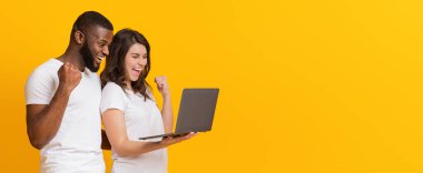 İnternet kazandı. Mutlu çok ırklı çift dizüstü bilgisayarla başarıya seviniyor, sarı arka planda heyecanla bağırıyorlar, boş alanlı panorama