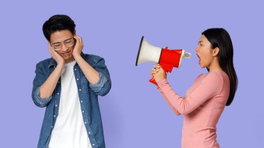 Çiftler arasında iletişim sorunları. Kızgın Asyalı kız, kızgın erkek arkadaşına megafonla bağırıyor, gri arka plan.