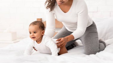 Afrikalı Amerikalı anne, küçük bebeğiyle oynuyor. Oğlunun evde emeklemesine yardım ediyor. Anne, Toodler Kid 'e Bakıyor Annelik rutininin tadını çıkarıyor