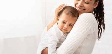 Mutlu Afrikalı anne kucağında bebek kucağında küçük şirin kız pozu veriyor. Doğum izni, annelik ve mutluluk, çocuk bakımı. Anneler Konsepti sever. Kırpılmış