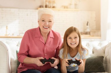 Aile aktiviteleri. Mutlu çocuk ve büyükannesi evde video oyunu oynuyorlar.