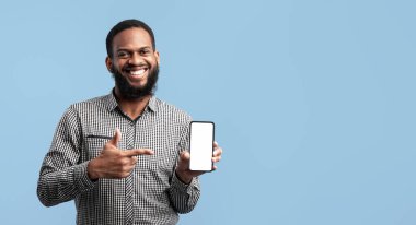 Bu aygıtı tavsiye ediyorum. Elinde beyaz ekranı olan akıllı telefonu tutan ve onu gösteren gülümseyen sakallı siyah adam. Modelleme için boş bir alan gösteriyor. Mavi arka planda izole edilmiş.