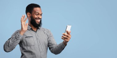 Mutlu Afrikalı adam telefonla video çekiyor ve arayana el sallıyor, Mavi Turkuaz Stüdyo Duvarı, bedava alan