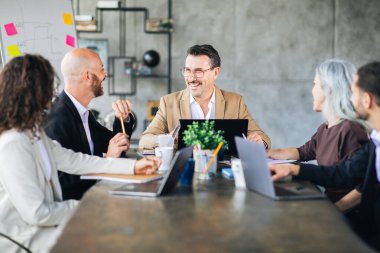 A group of professionals engaged in a lively discussion around a conference table in a contemporary office. Each member contributes ideas with enthusiasm, fostering collaboration. clipart