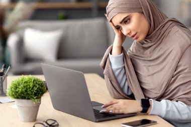 İlham eksikliği. Laptop 'ta çalışan yorgun Arap Serbest Çalışan Kadın, Masasında Üzgün İfadesiyle oturan, Acı çeken İş Sorunları, İş Bulma veya İş Fırsatları İnternetteki