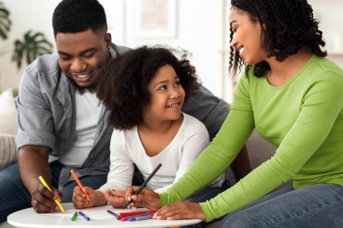 Küçük kızlarıyla resim çizen mutlu siyahi ebeveynler birlikte vakit geçirmenin keyfini çıkarıyorlar.