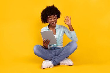 Pembe Stüdyo Arkaplanı Üzerinde Oturarak, Sayısal Tablet 'in Bilgisayar Kamerasına El sallayarak İnternet üzerinden İletişim kurduğu Genç Afrikalı Kadın Videosu. Modern İletişim Konsepti