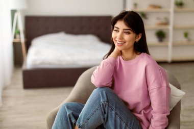 Rahatlayın ve rahatlayın. Gülümseyen kadın modern gri koltukta dinleniyor, pencereye bakıyor, sakin kadın dinleniyor ve geleceği hayal ediyor, planları düşünüyor, bulanık arka plan, seçici odaklanma.