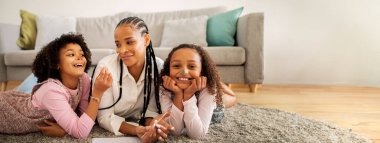 Siyahi bir anne, iki kızıyla neşeyle etkileşime girer. Oturma odalarında yerde neşeyle yatarlar. İçleri sıcak ve aile bağlarıyla doludur..