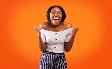 Öyle mi? Heyecanlı Afro Kadın Bağıran Yumruklar Turuncu Arkaplanda Duruşunu Kutluyor. Stüdyo Çekimi