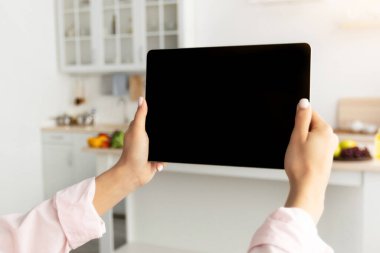Modern mutfakta duran, siyah boş ekranlı dijital tableti olan genç bir kadının omuz manzarası üzerinde. Teknoloji, Şablon, Otomasyon, Akıllı Ev Kavramı