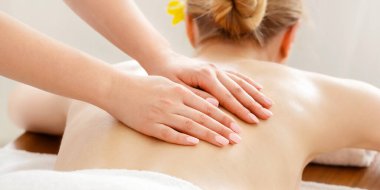 Rahatla ve kaplıcaya git. Beyaz çarşaf ve orkideyle masaj masasındaki çıplak kızın sırtındaki kadın elleri.