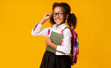 Okula geri dön. Sarı Stüdyo Arkaplanındaki Kameraya Gülümseyen Afro İlköğretim Öğrenci Kız Kucağında Mutlu Yıllar. Boş Alan