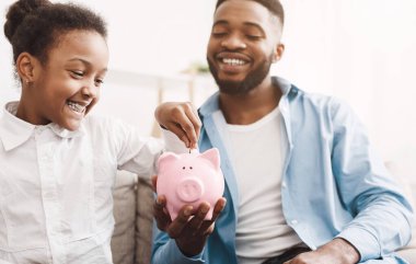 Kişisel Tasarruflar. Küçük Afro Kız Piggybank için Para Koyarak, Baba Holding It