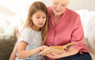 Birlikte okuyoruz. Yaşlı kadın ve torununun evdeki kanepede ilginç bir kitabı var.