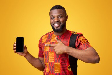 Pozitif Afro-Amerikan adam boş akıllı telefon ekranını işaret ediyor, yeni mobil uygulama öneriyor, sarı stüdyo geçmişi
