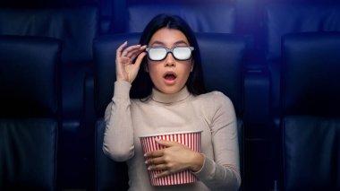 Üç boyutlu gözlüklü korkmuş Asyalı kadın sinemada korku filmi izliyor.