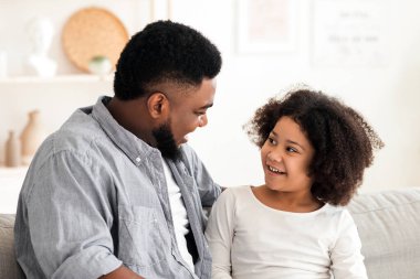 Siyah babayla ilgilenmek, küçük kızına dizüstü bilgisayarın nasıl kullanılacağını öğretmek, evdeki koltukta birlikte oturmak...