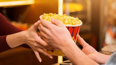Sinema ve eğlence. Sinemadaki tezgahtardan patlamış mısır alan genç bir adam.