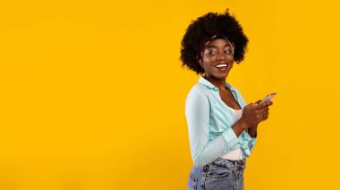 Neşeli Afrikalı Afro-Amerikalı Kadın, fotokopi odasına yan bakan akıllı telefon kullanıyor. Pembe Stüdyo Arkaplanı 'na poz veriyor. Cep telefonu iletişimi, telefonunuz için yeni uygulama. Panorama
