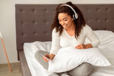 Hafta sonunun tadını çıkarıyorum. Çekici gülümseyen Afrikalı Amerikalı kadın portresi müzik dinliyor, kablosuz kulaklık takıyor ve cep telefonu kullanıyor, sabahları yatakta seans yapıyor, bedava fotokopi çekiyor.