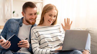 Çevrimiçi parti. Genç çift evdeki bilgisayardan arkadaşlarıyla görüntülü iletişim kuruyor.