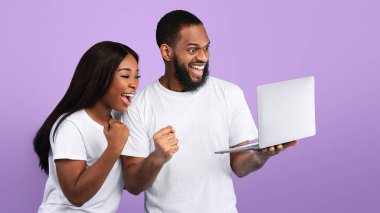 Öyle mi? Heyecanlı siyah çiftin portresi online galibiyeti kutluyor, büyük bir iş başarısı, dizüstü bilgisayarı tutuyor ve kullanıyor, bağırıyor ve yumruklarını sallıyor, siyah stüdyo duvarı, afiş.