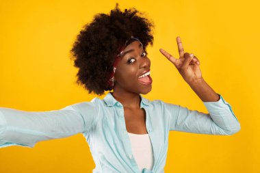 Bushy Afro-Amerikan Genç Kadın Selfie Çekiyor V işareti Pembe Stüdyo Arkaplanı, Kameraya Gülümseme. Başarılı Milenyum Kadınları Zafer İşareti Gösteriyor.