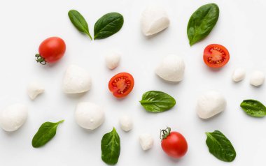 Beyaz arka plan üzerinde kiraz domates, fesleğen ve peynir yapılmış renkli caprese malzemeler desen. Caprese salata tarifi konsepti, üstte görmek