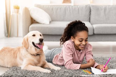 Güzel Afrikalı Amerikalı kız yerde yatıyor, altın renkli halısı ve çizimi olan, evde kalemlerle resim yapan, boş zaman ve hobi aktivitelerinin keyfini çıkaran, bedava fotokopi alanı olan sevimli bayan çocuk.