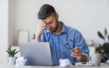 Gözler yorgunluğu. Çok çalışan işadamı ofiste geçirdiği uzun iş gününden sonra yoruldu, işyerinde oturuyor, burun köprüsüne masaj yapıyor, iş sorunları yaşıyor.