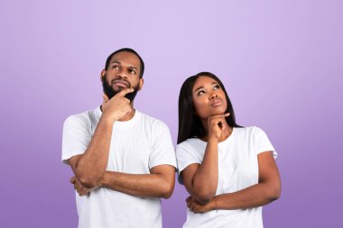 Düşünceli Afrikalı Amerikalı bir çiftin portresi. Düşünen, bakan, dokunan, mavi stüdyo arka planında tek başına duran. Düşünceli siyah erkek ve kadın karar veriyor.