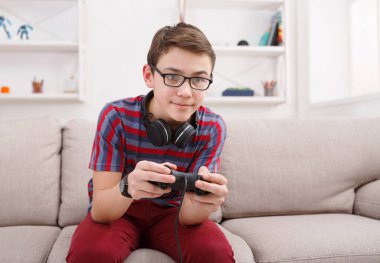 Oyun video oyunları kavramı - genç çocuk oyun çubuğu ve evde oturma odasında kanepede oturan zevk kulaklık, futbol oyun oynuyor