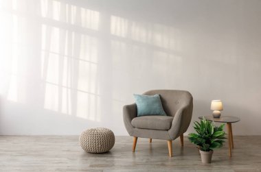Yastıklı rahat bir koltuk, masada parlak bir lamba, saksıda bitki ve oturma odasında gri duvarda bir kanepe. Eski mobilyaları olan çağdaş tasarım, İskandinav tarzı, hiç kimse