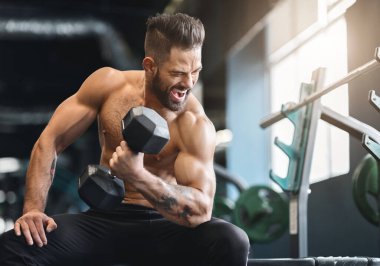 Sert güç egzersizi. Çıplak vücut geliştirmeci spor salonunda dumbbell ile egzersiz, boş alan