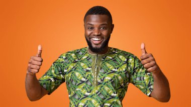 Yeşil Afrikalı tişörtlü mutlu siyah adam sarıya başparmak gösteriyor.