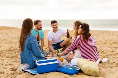Beş arkadaşından oluşan bir grup kumlu sahilde gevşeyip abur cubur ve içkileri paylaşıyor. Gülüp sohbet ediyorlar, okyanus dalgalarının arka planında birbirlerine eşlik ederek eğleniyorlar..
