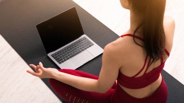 Salgın sırasında kendini soyutlama. Online yoga dersinden sonra nefes alma egzersizleri ya da meditasyon yapan genç bir kadın. Dizüstü bilgisayar ekranında tasarım için bir model