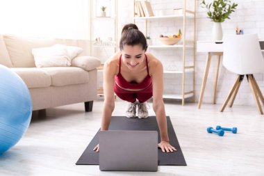 Aktif olarak evde kalıp eğlenin. Milenyum kızı çevrimiçi video derslerine kalas egzersizi yapıyor.