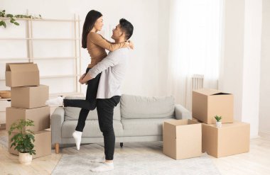 Taşınma gününü kutluyoruz. Mutlu Asyalı çift kucaklaşıyor, gülümsüyor. Güzel karısını kaldırıyor.