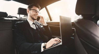 Her zaman temastayız. Takım elbiseli, kendine güvenen bir yönetici. Kişisel bilgisayar kullanıyor ve takside telefon görüşmesi yapıyor. Kopya alanı, işaret fişeği ışığı.