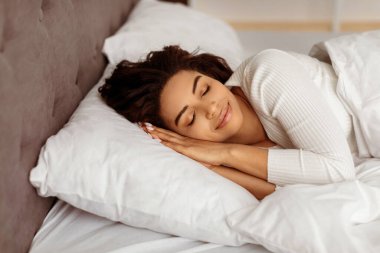 Sıcak uyku zamanı konsepti. Yan tarafta uyuyan sakin Afrikalı Amerikalı kadının yakın plan portresi. Güzel siyah bayan yorgan altında dinleniyor, rahat yatağında şekerleme yapıyor.