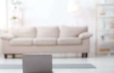 Evde kal ve blog için koç olarak çalış. Dizüstü bilgisayar, yerde spor paspas ve oturma odasının içindeki kanepe bulanık, kapat, kopyala alanı