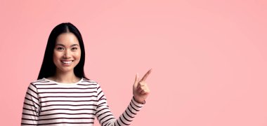 Şuna bak. Gülümseyen Asyalı genç bayan dizüstü bilgisayarla oturuyor ve fotokopi stüdyosunun arka planında boşluğu işaret ediyor Koreli kadın tasarımın veya reklamın için bedava yer gösteriyor, Panorama