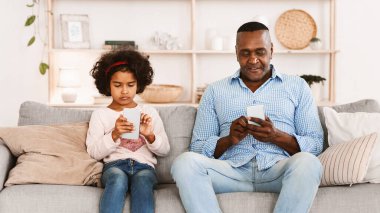 Gadget aşırı kullanım sorunu. Kıdemli Afro-Amerikan adam ve torununun evde akıllı telefonları var.