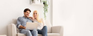 Mutlu Genç Eşler Laptop Satın Alma Mobilyalarını Evdeki Koltukta Oturmak İçin Kullanıyor. Metin için Boş Alan